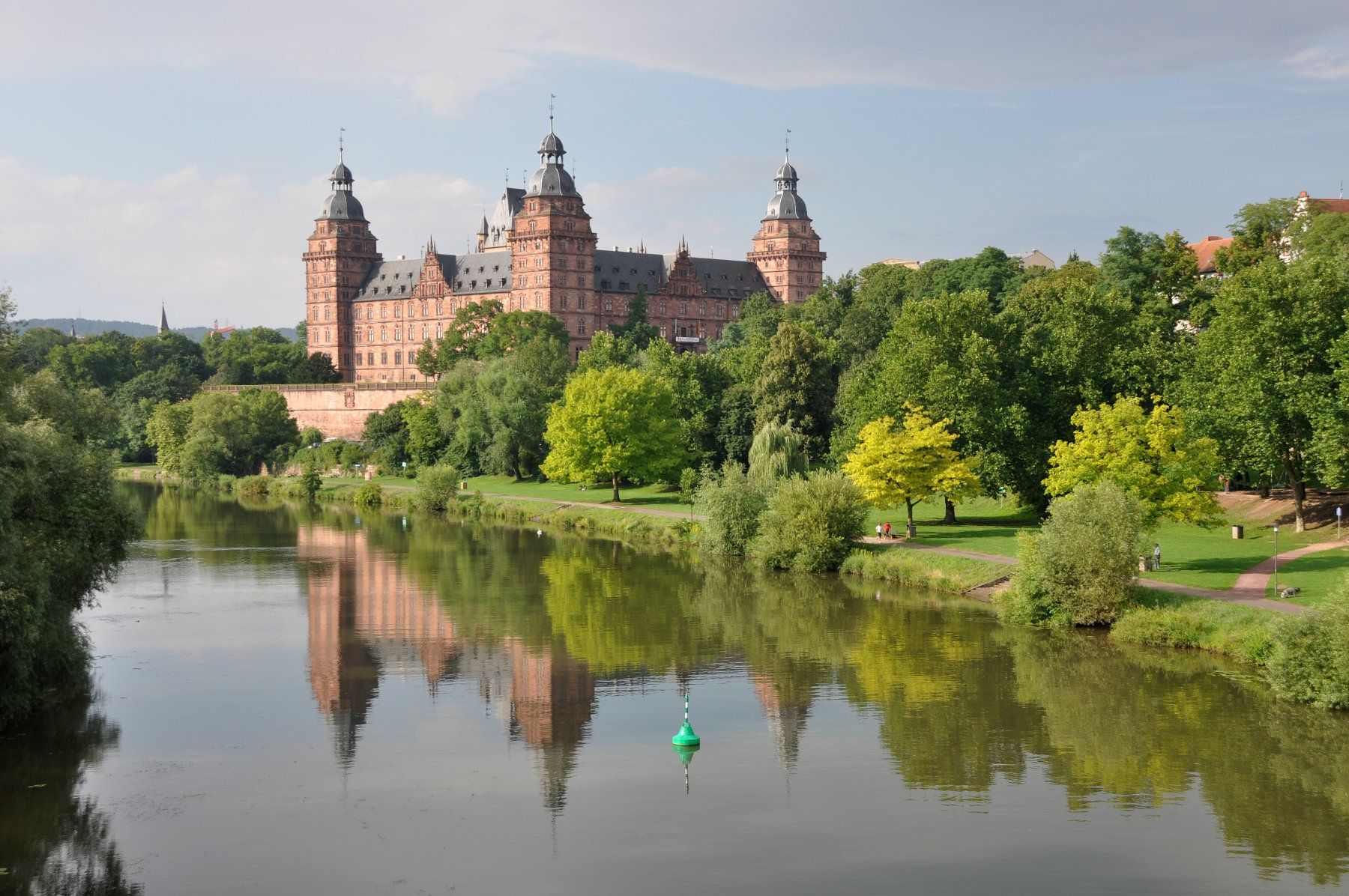 a large building sitting on top of a lush green field next to a river